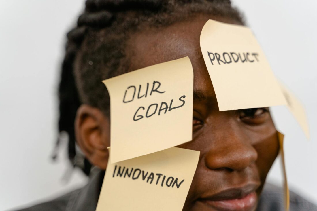 Close-up of person with sticky notes on forehead, symbolizing creative brainstorming and innovation.