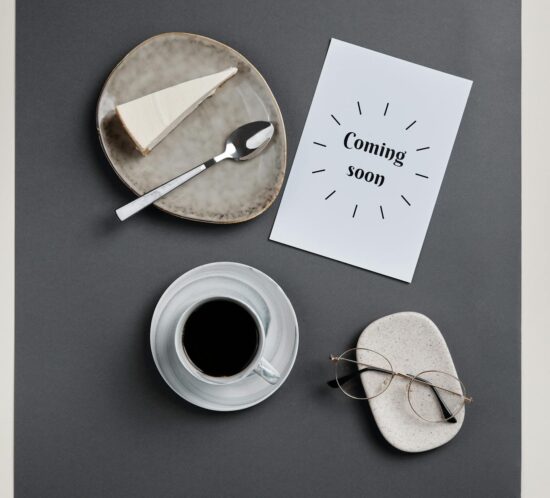Stylish flatlay featuring coffee, slice of cheesecake, and eyeglasses on paper.